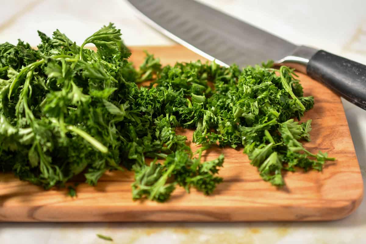 chopped parsley on a cutting board with a knife.