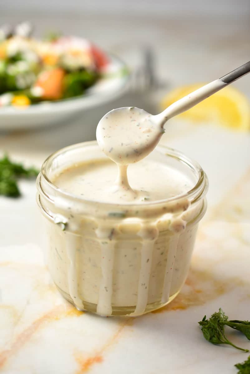 creamy Texas Roadhouse ranch dressing dripping off a spoon in a cup. 