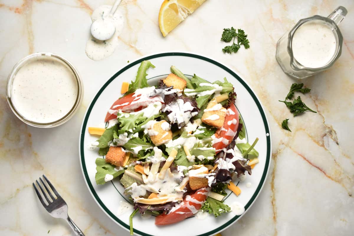 salad with ranch dressing and two bowls of dressing on the side. 