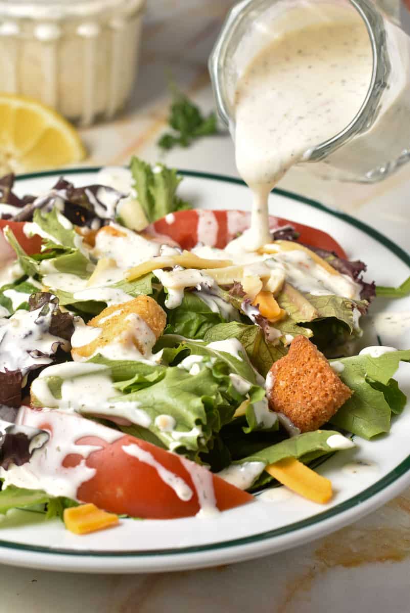 Texas roadhouse ranch dressing being poured over a salad. 