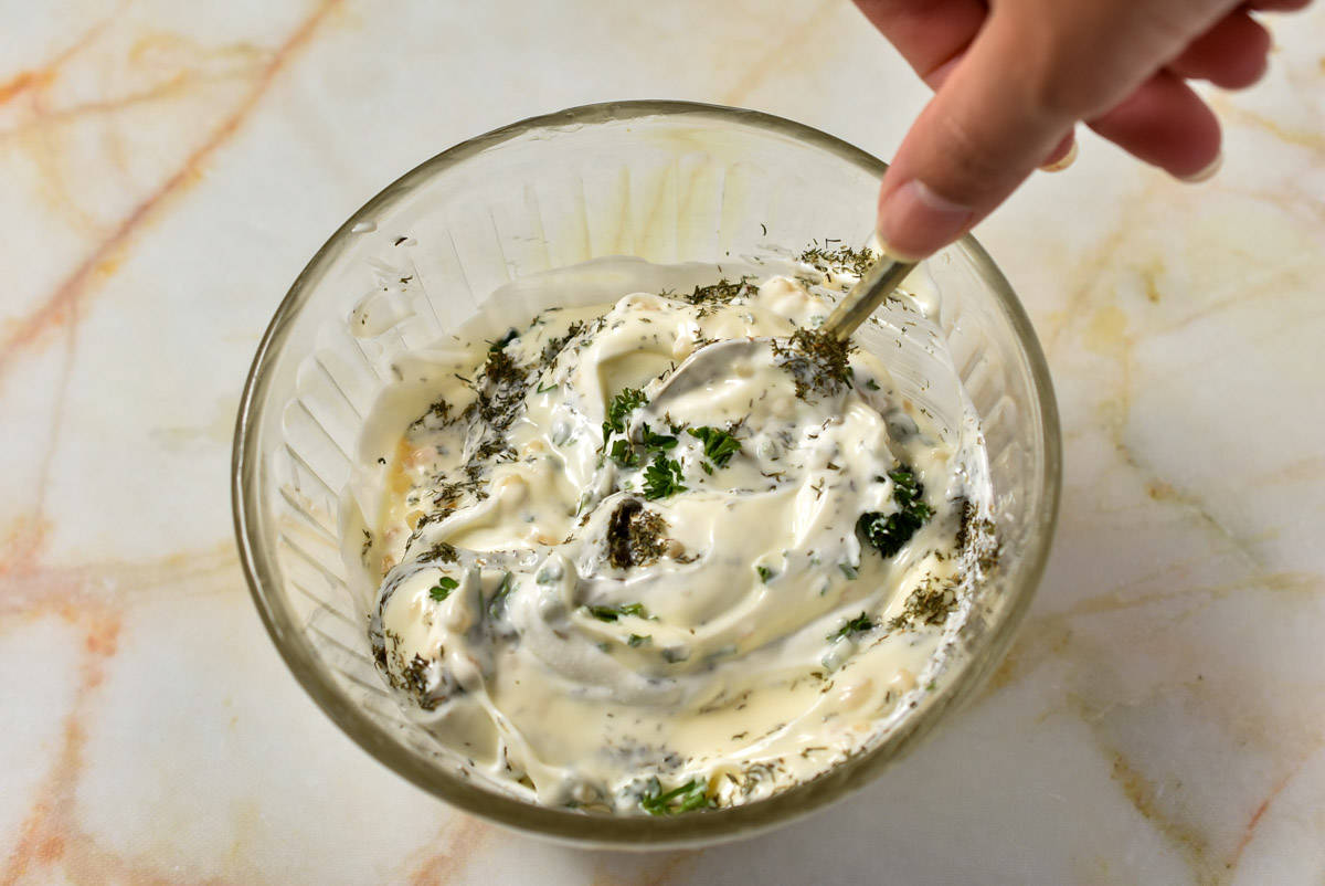spoon stirring mayo mixture together with herbs. 