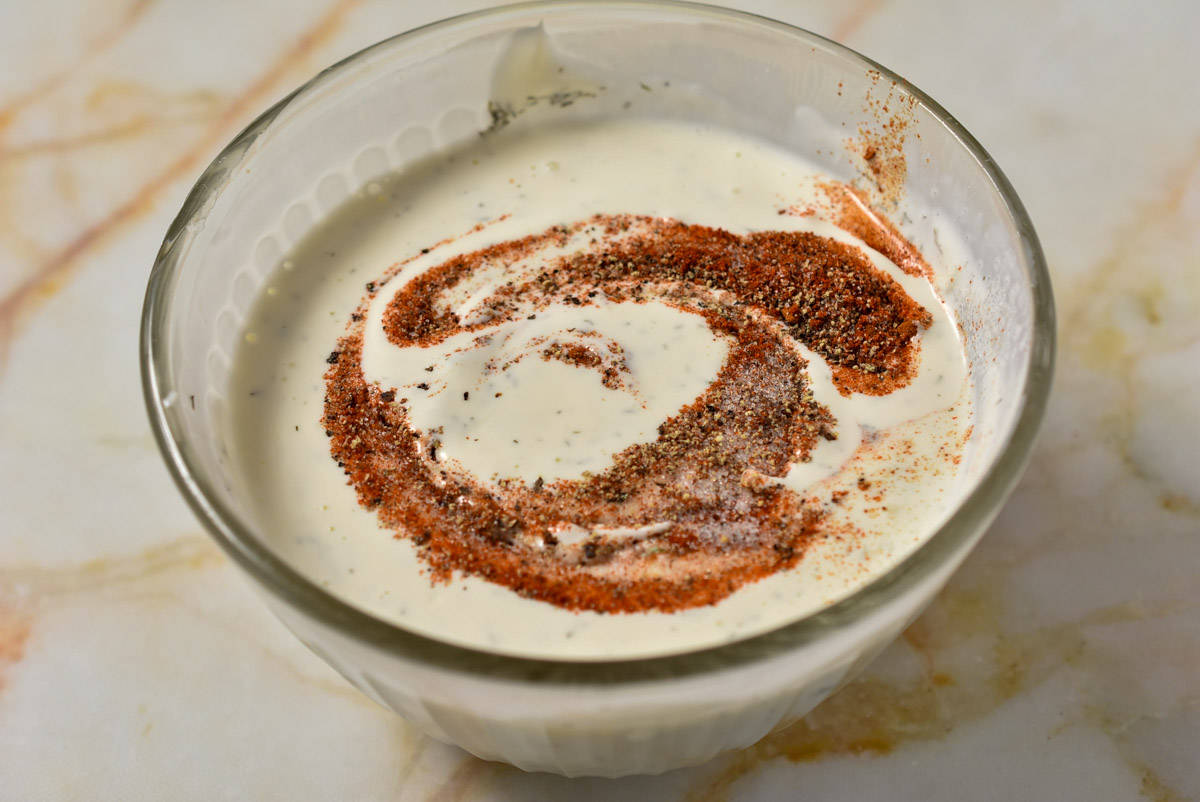 ranch dressing with spices and buttermilk in a mixing bowl. 