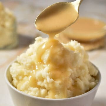 spooning popeye's gravy onto a small bowl of mashed potatoes.