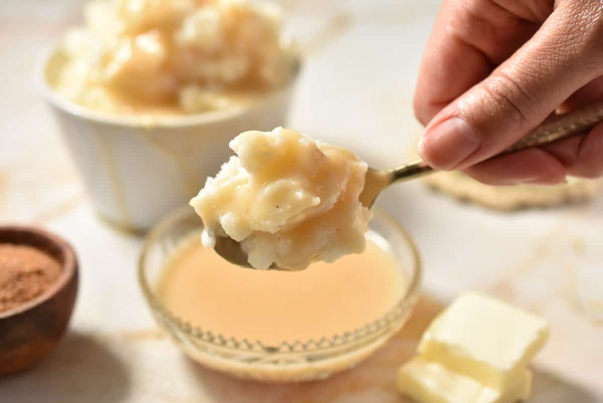 a spoon with mashed potatoes and creamy gravy poured over.