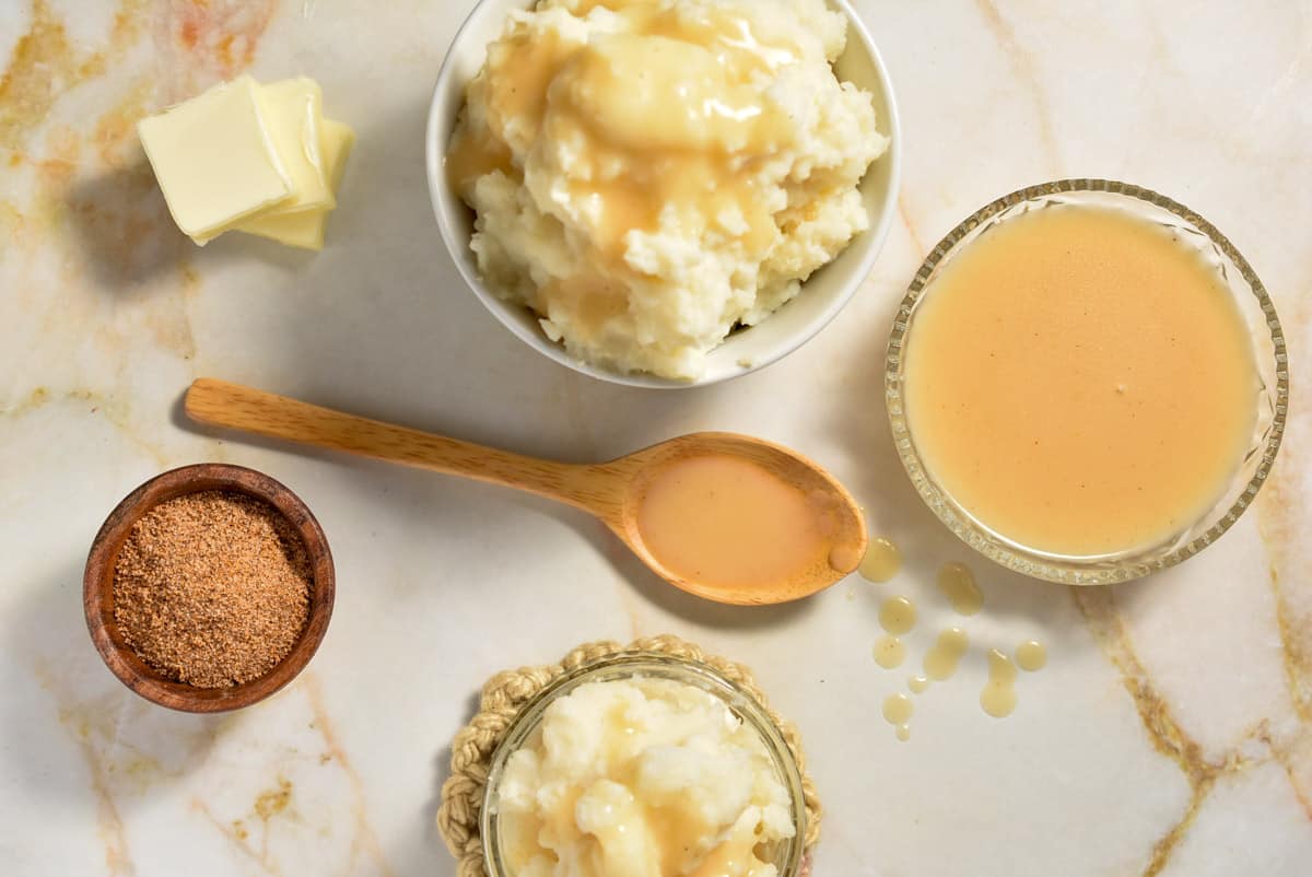 a bowl of popeye's gravy next to a bowl of mashed potatoes smothered with gravy.