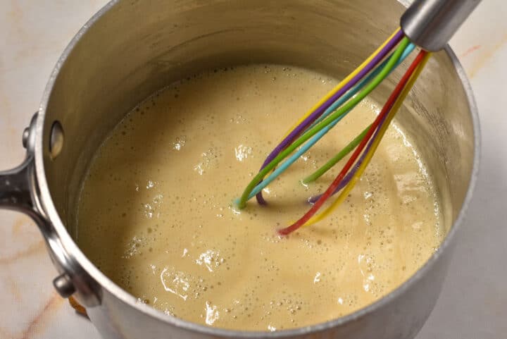 bubbling blond roux mixture in a pot with a whisk.