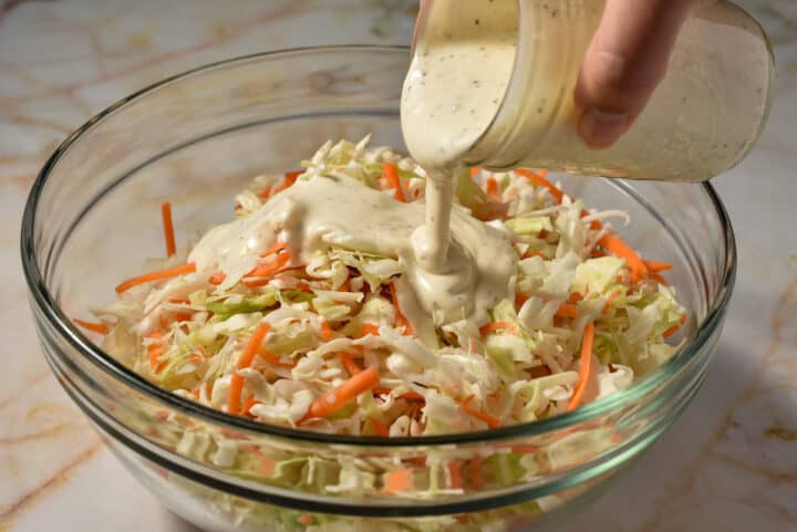 Creamy sauce being poured over the Dole coleslaw mix.
