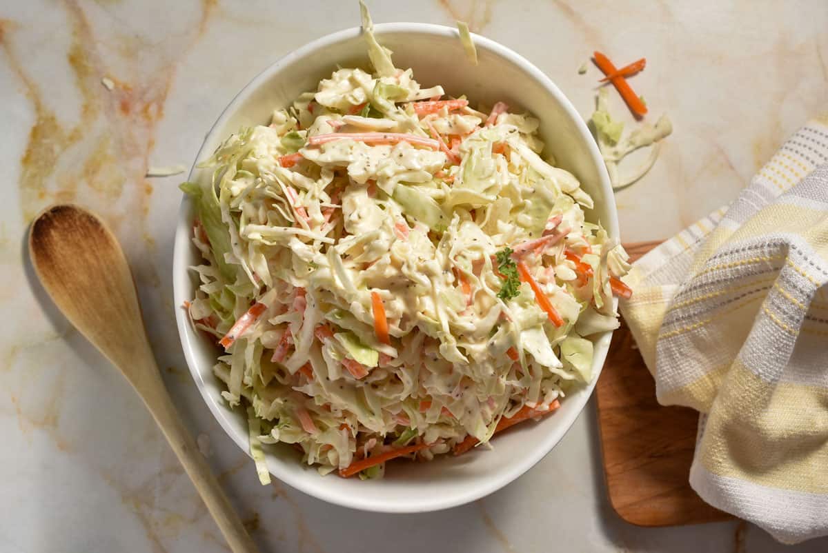 A white bowl with coleslaw including shredded cabbage and creamy mixture.