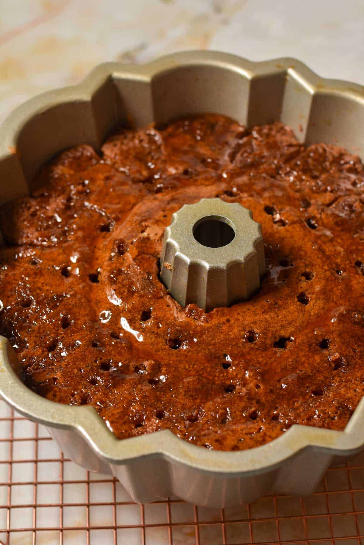 cake in a bundt pan with holes poked in the top and glaze poured over. 