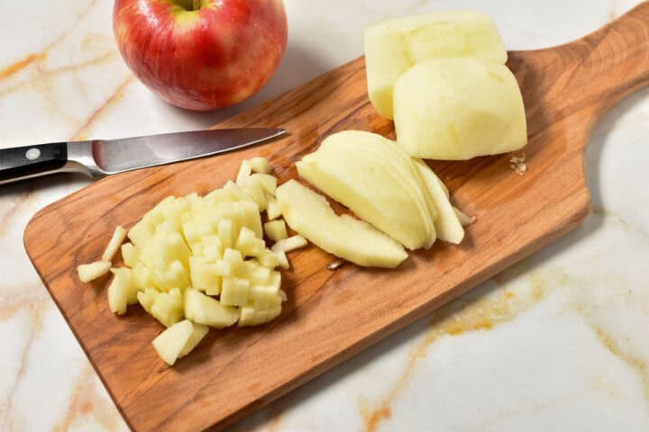 peeled apples sliced on a wooden cutting board.