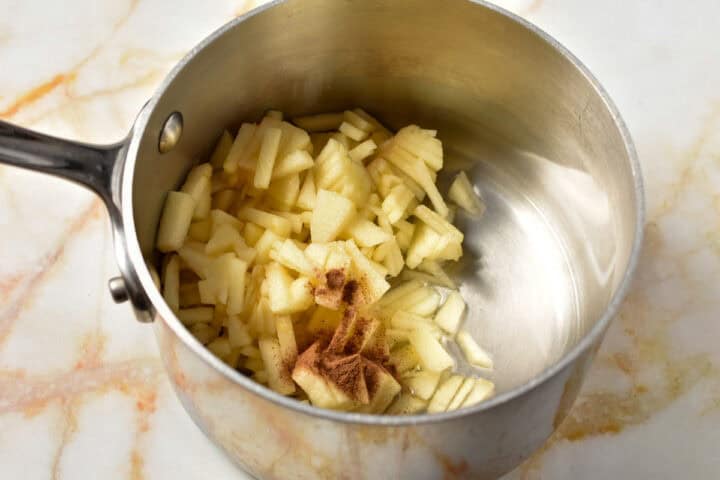 sliced apples with cinnamon and sugar in a pan.