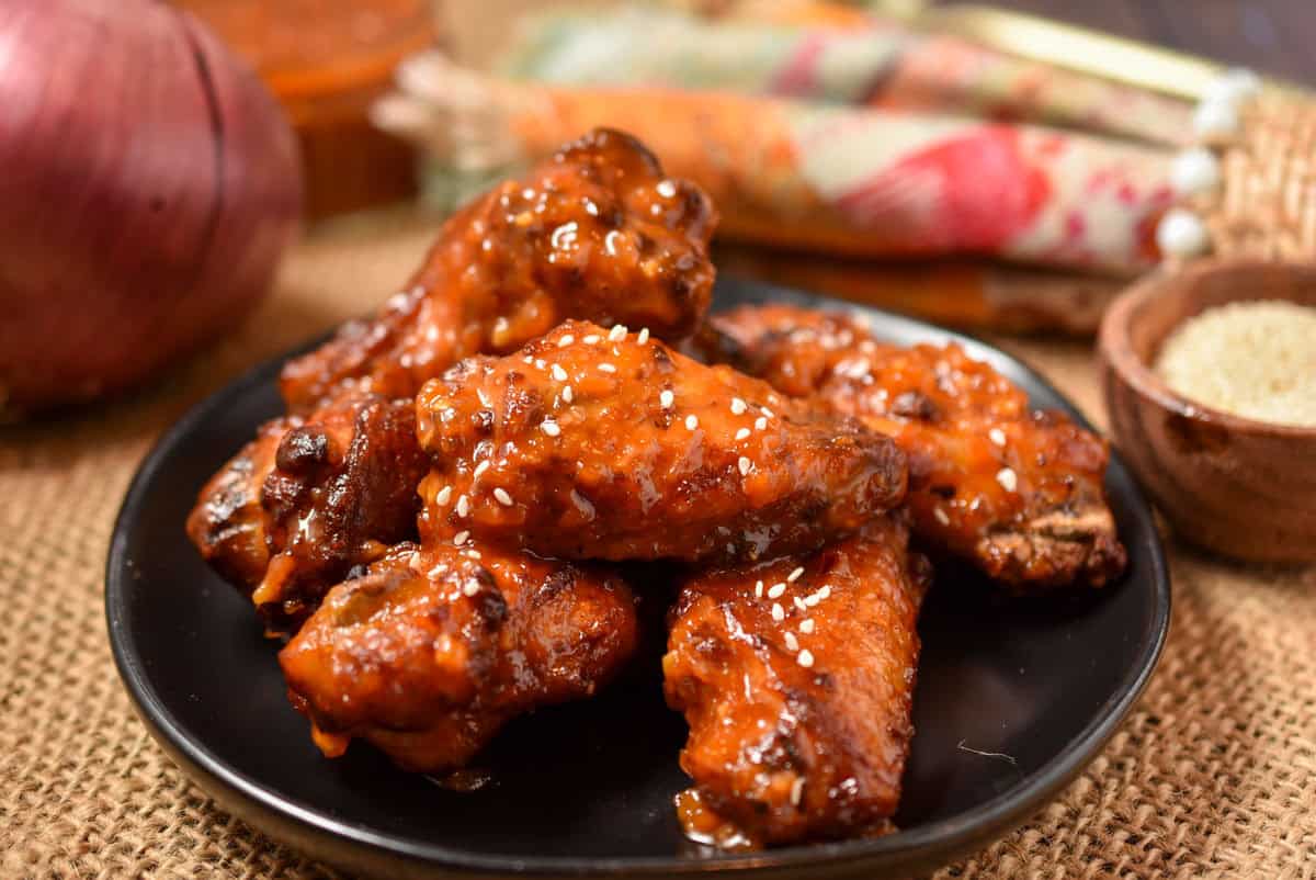 Asian zing sauce covering a plate stacked with chicken wings.