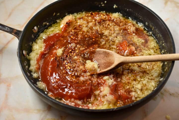skillet with additional ingredients added with a spoon mixing together.