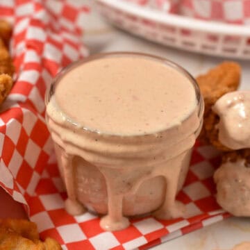 bo sauce in a bowl with chicken tenders and french fries on a platter.