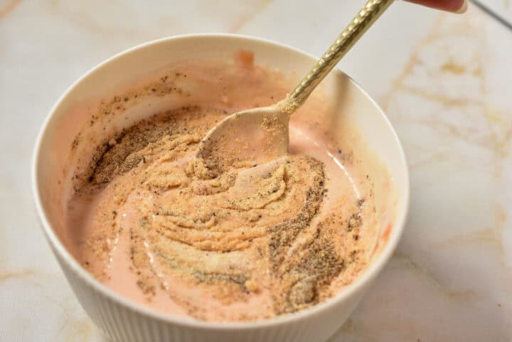 spice mixture being mixed into mayo mixture with a spoon.