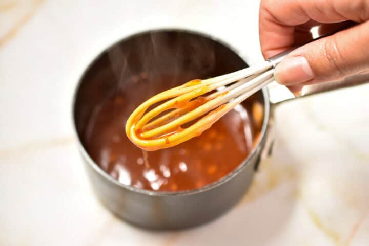 process shot of the whisk with McDonald's sweet chili sauce dripping off.