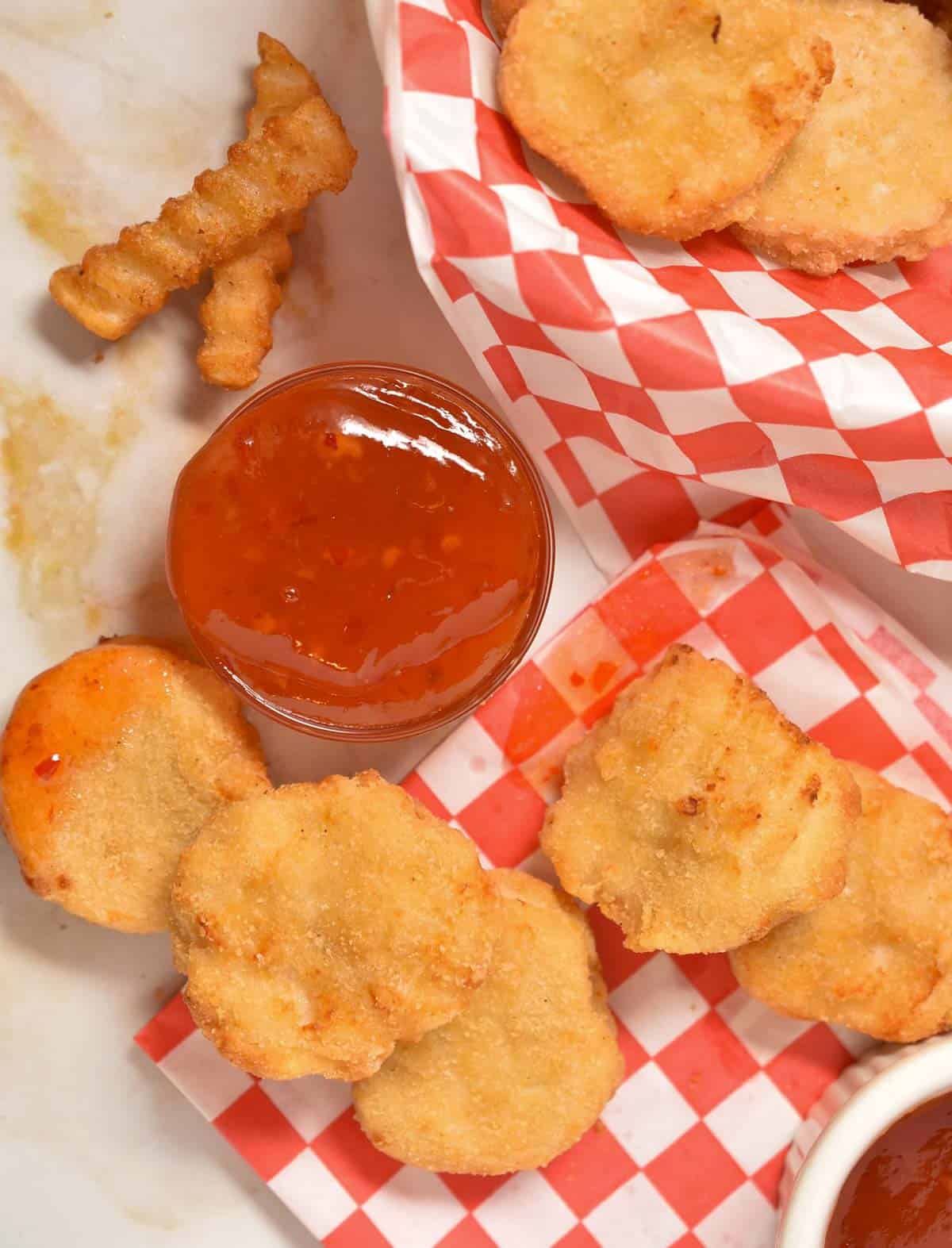 clear bowl of chili sauce with french fries and chicken nuggets.