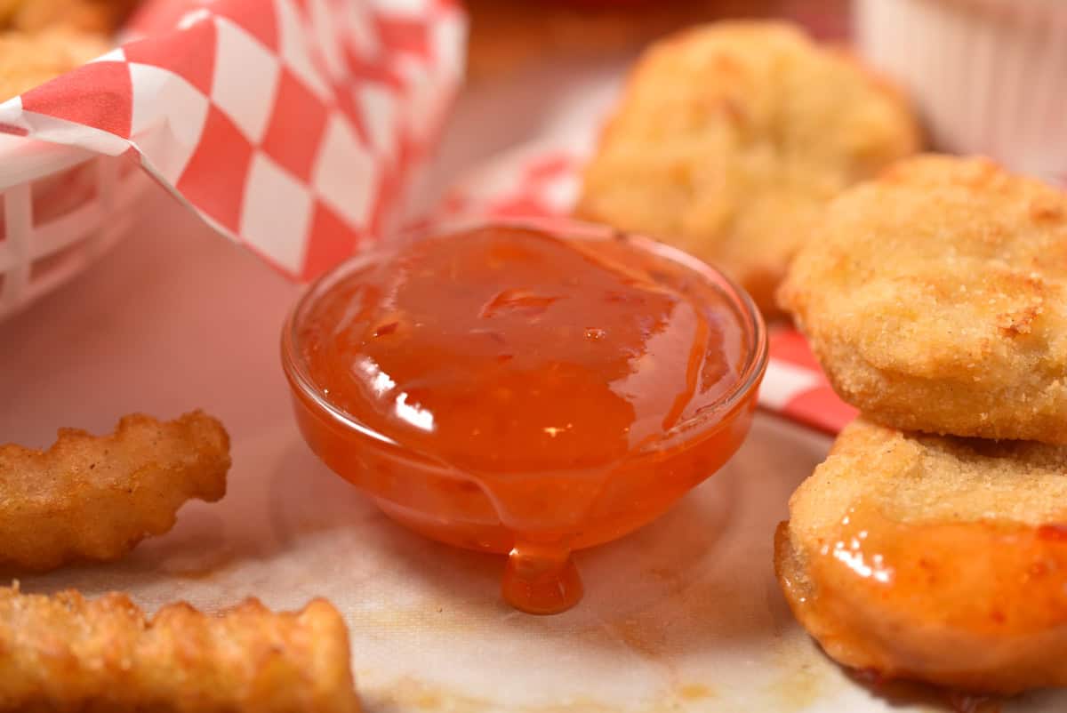 clear bowl of McDonald's sweet chili sauce with some dripping off the side.