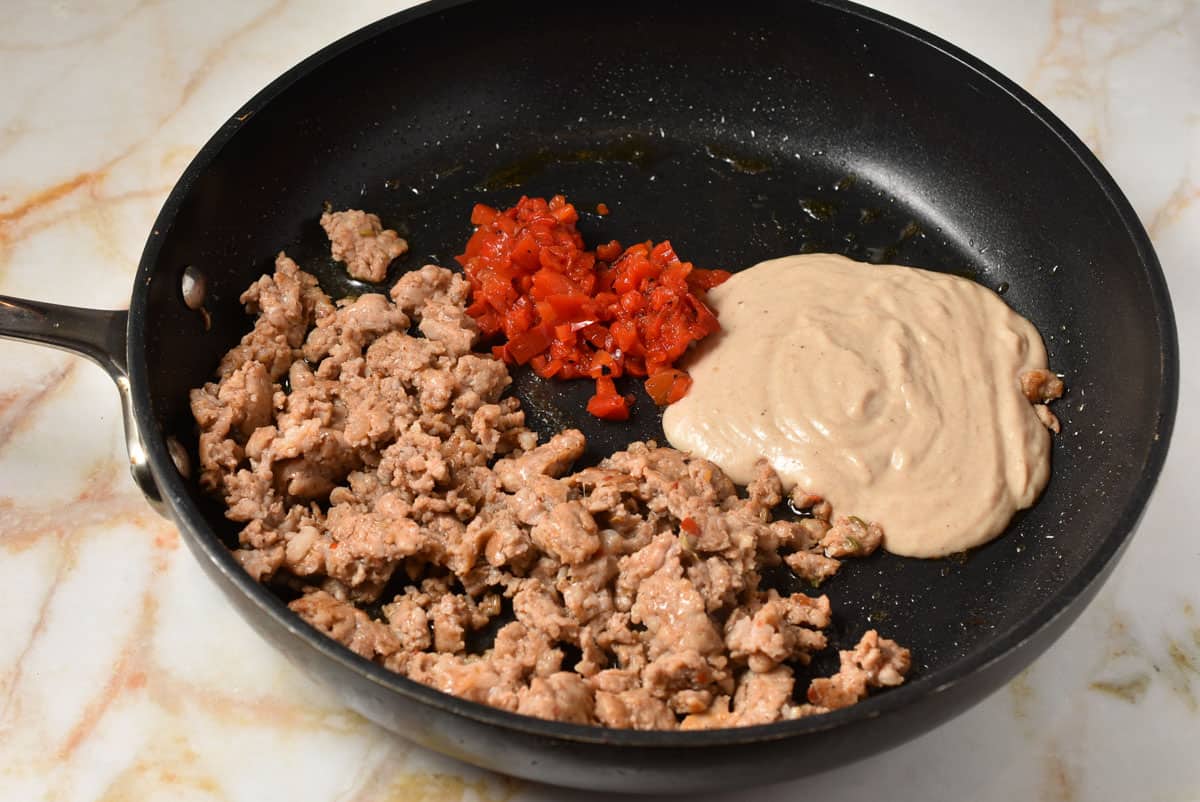 tukey sausage, red peppers, and bechamel sauce in a skillet.
