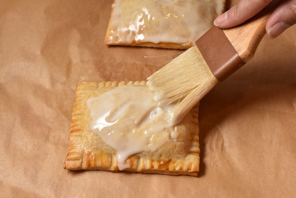 Pastry brush spreading the glaze onto the pie after baking.