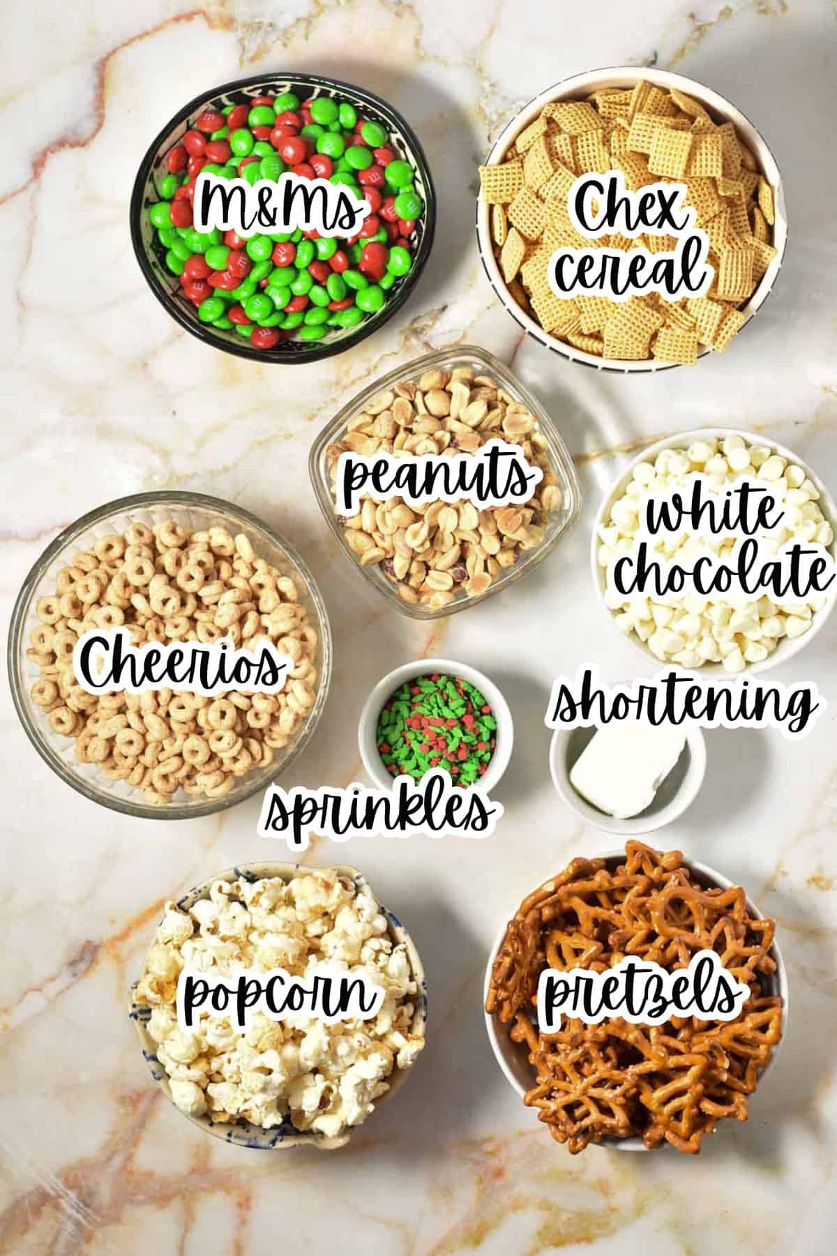 ingredients for reindeer food, including red and green m&m's, check mix, peanuts, popcorn, white chocolate, pretzels, and shortening.