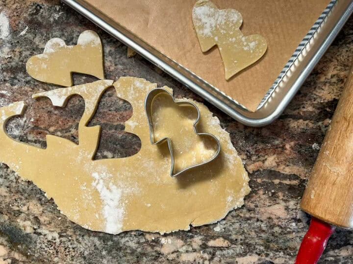 sugar cookie dough rolled out with heart shapes cut out.
