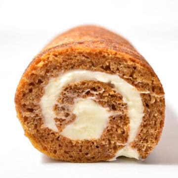 A close-up view of an Easy Pumpkin Roll cake with cream cheese filling, showing the spiral pattern-perfect for a make-ahead Thanksgiving dessert.