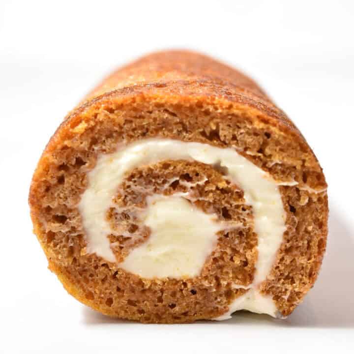 A close-up view of an Easy Pumpkin Roll cake with cream cheese filling, showing the spiral pattern-perfect for a make-ahead Thanksgiving dessert.